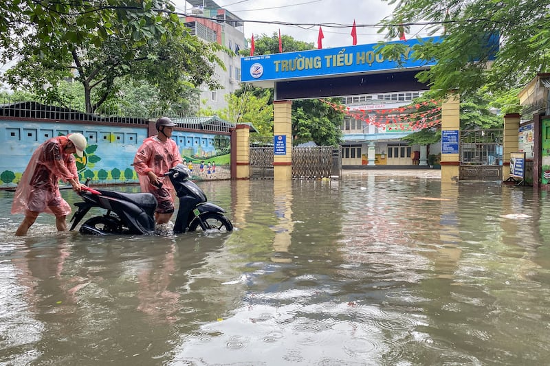 People push a motorcycle as they wade through a flooded street amid heavy downpours from Typhoon Matmo.