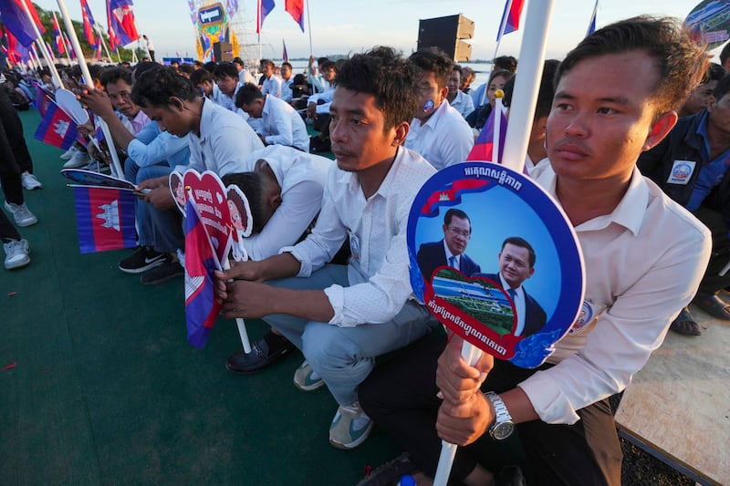 Cambodian civil servants hold photographs of Prime Minister Hun Manet and his father during a groundbreaking ceremony of China-funded Funan Techo canal, Aug. 5, 2024. (Heng Sinith/AP)