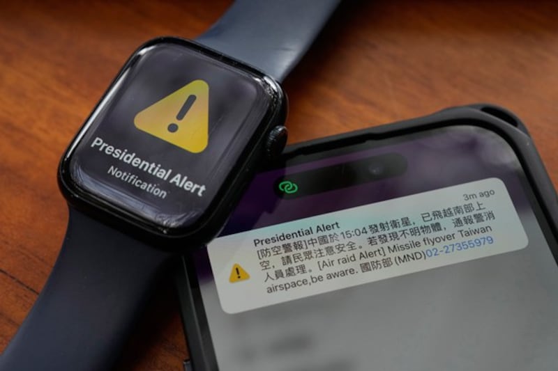 A phone and watch display Taiwan's air raid alert on Jan. 9, 2024. The Ministry of National Defense text alert about a Chinese satellite launch caused alarm because the English part of the text referred to the rocket as a 'missile.' (Ng Han Guan/AP)