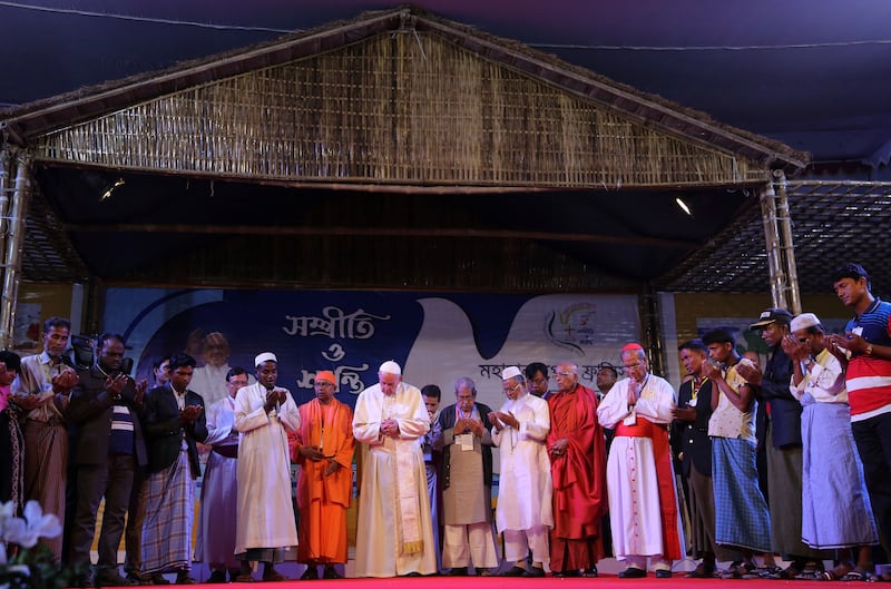 A Rohingya Muslim refugee from Myanmar, center left in white robe, leads a prayer with Pope Francis at an interfaith peace meeting in Dhaka, Bangladesh, Dec. 1, 2017.